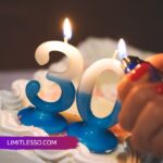 Lit number 30 candles on a frosted cake, hand holding a lighter.