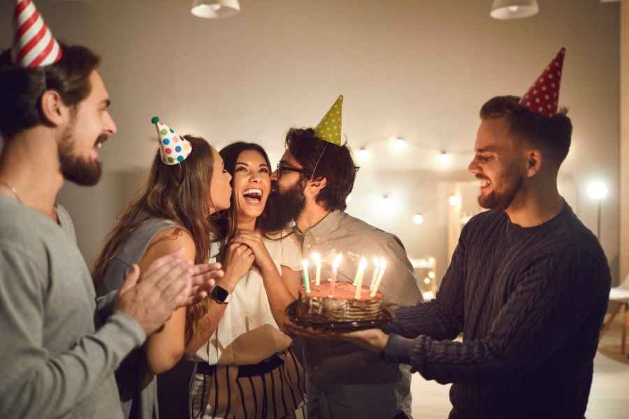 A group of friends candles on a cake and laughing in a a celebration mood